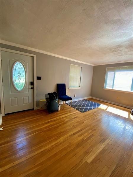 foyer featuring hardwood / wood-style flooring, ornamental molding, and a textured ceiling