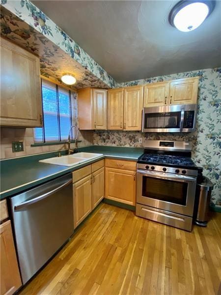 kitchen with sink, light wood-type flooring, light brown cabinets, and appliances with stainless steel finishes