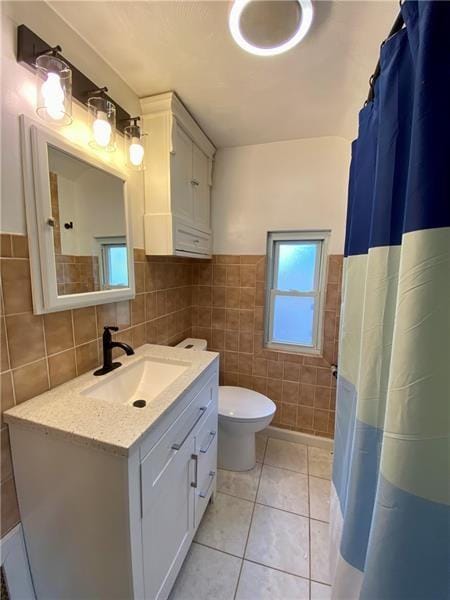 bathroom with walk in shower, tile patterned floors, toilet, vanity, and tile walls