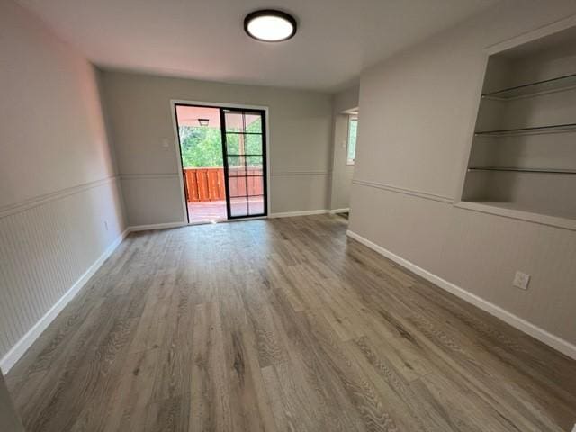 empty room featuring hardwood / wood-style floors and built in shelves