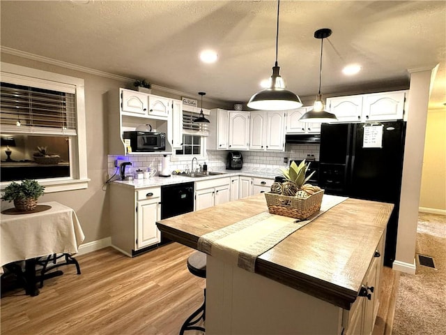 kitchen featuring white cabinets, a center island, decorative light fixtures, and black appliances