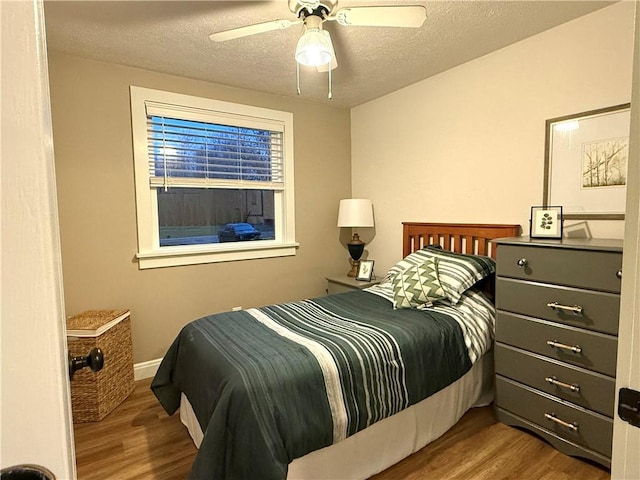 bedroom with a textured ceiling, dark hardwood / wood-style flooring, and ceiling fan