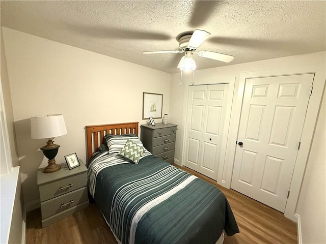 bedroom with ceiling fan, dark wood-type flooring, and a textured ceiling