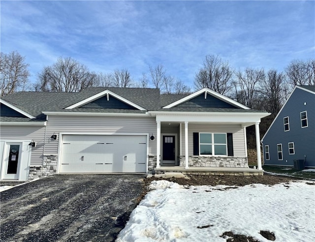 view of front of property featuring a garage, central AC unit, and covered porch