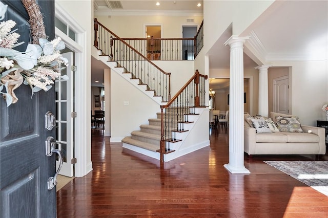 entrance foyer featuring ornate columns, dark wood-type flooring, and ornamental molding