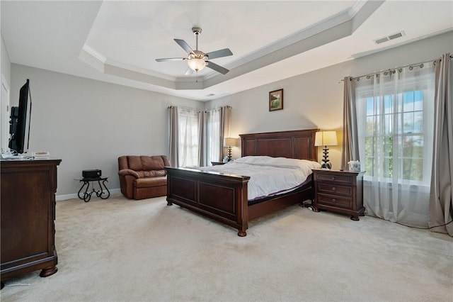 carpeted bedroom featuring multiple windows, ornamental molding, ceiling fan, and a tray ceiling