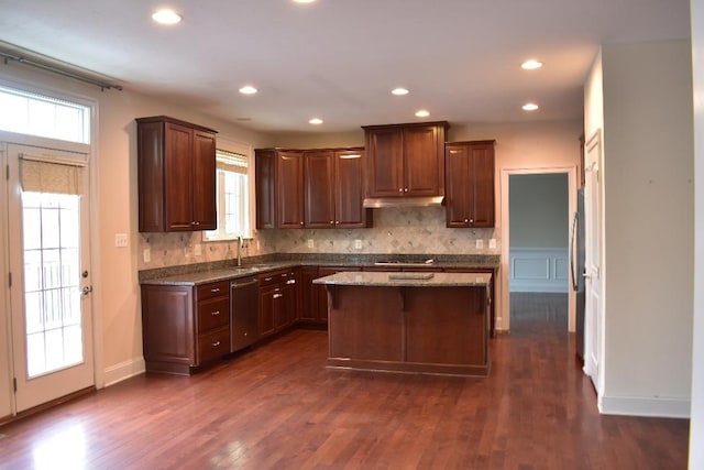 kitchen featuring sink, appliances with stainless steel finishes, backsplash, light stone counters, and a kitchen island