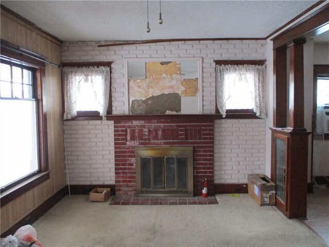 living room featuring a fireplace, light colored carpet, a wealth of natural light, and brick wall