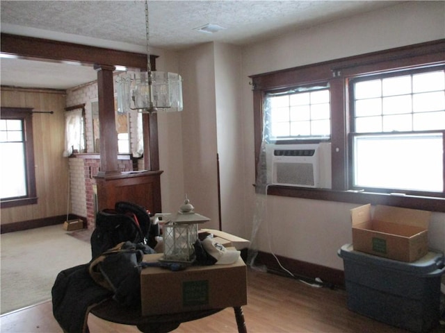 dining room featuring decorative columns, cooling unit, wood-type flooring, and a textured ceiling