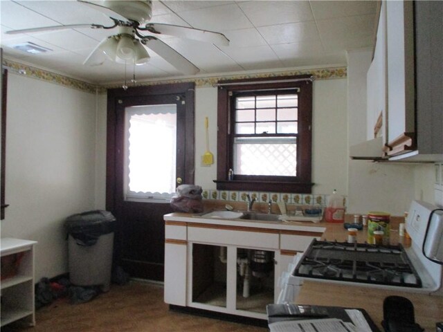 kitchen featuring a wealth of natural light, white cabinetry, sink, and white range with gas cooktop