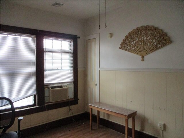 dining space with hardwood / wood-style floors, wood walls, and cooling unit