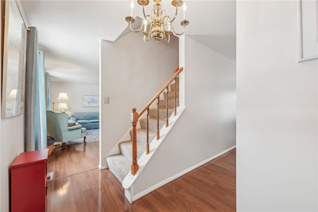 stairway featuring hardwood / wood-style floors and an inviting chandelier