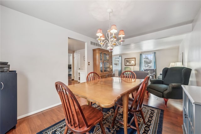 dining space with dark wood-type flooring and a chandelier