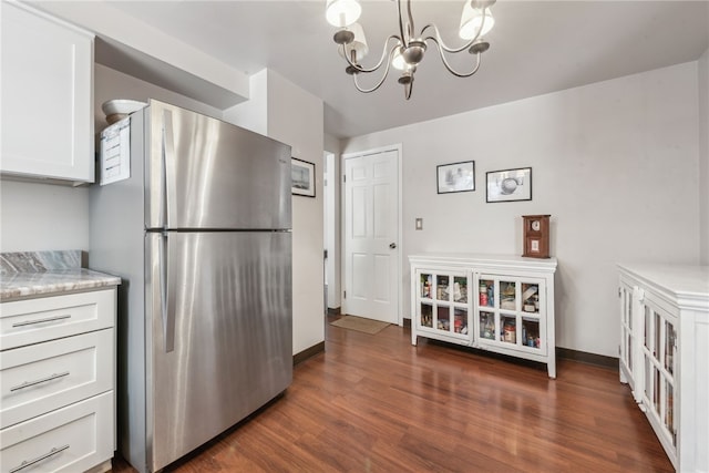 kitchen with dark wood-type flooring, pendant lighting, a chandelier, white cabinetry, and stainless steel refrigerator