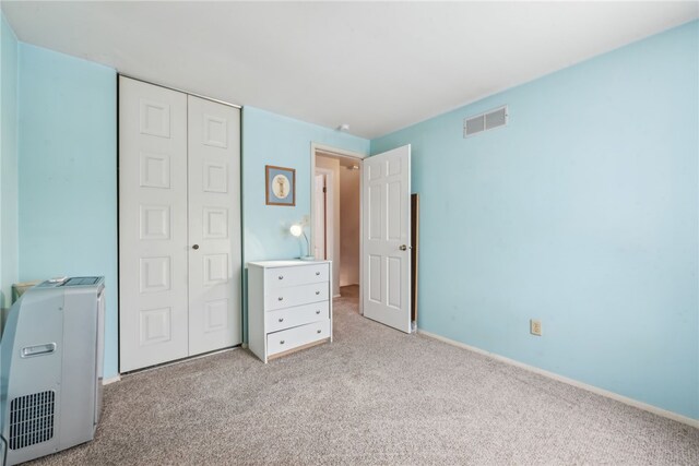 unfurnished bedroom with light colored carpet and a closet