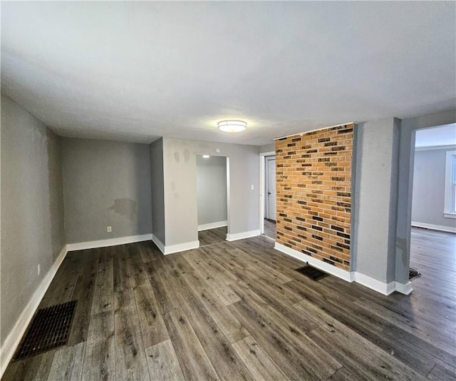 interior space with dark wood-style flooring, visible vents, and baseboards