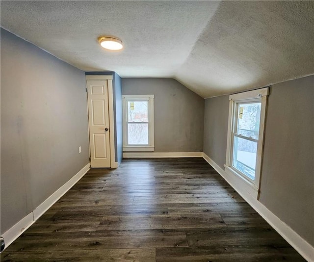 bonus room featuring dark wood finished floors, a textured ceiling, and baseboards