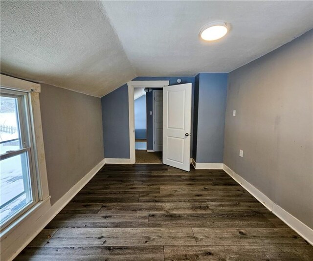 bonus room with dark hardwood / wood-style floors, a textured ceiling, and vaulted ceiling