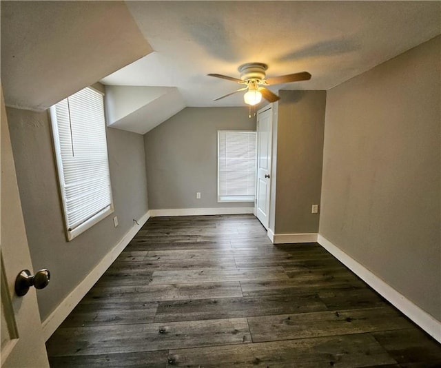 bonus room featuring dark wood-type flooring, vaulted ceiling, baseboards, and a ceiling fan