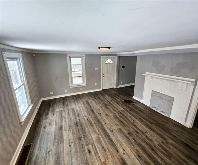 unfurnished living room featuring dark wood-type flooring and a brick fireplace