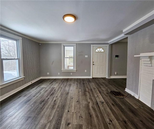 entryway featuring crown molding, dark wood-type flooring, a brick fireplace, and baseboards