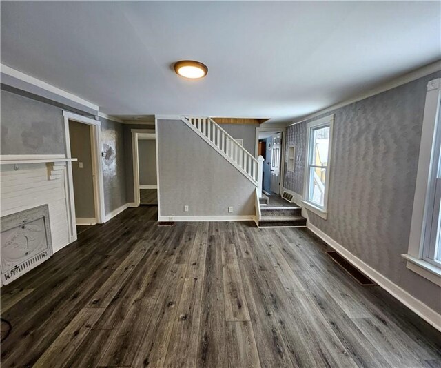 unfurnished living room featuring dark hardwood / wood-style flooring and a brick fireplace