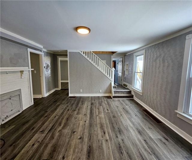 unfurnished living room featuring baseboards, stairway, and dark wood finished floors