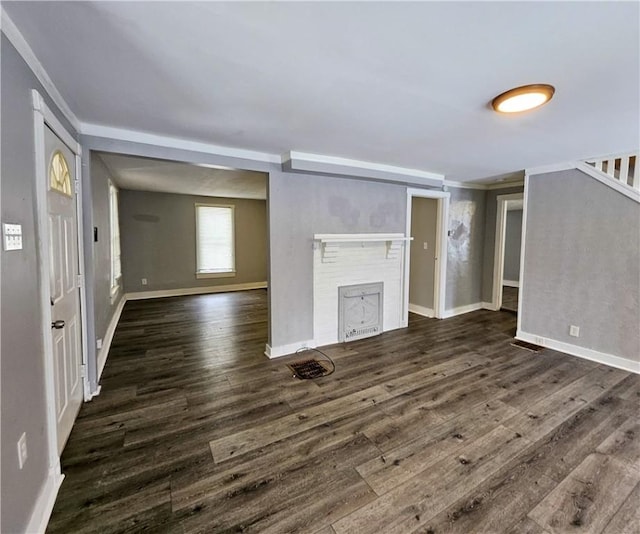 unfurnished living room featuring a fireplace, dark wood-type flooring, and ornamental molding