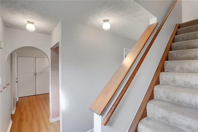 stairs featuring a textured ceiling and hardwood / wood-style flooring