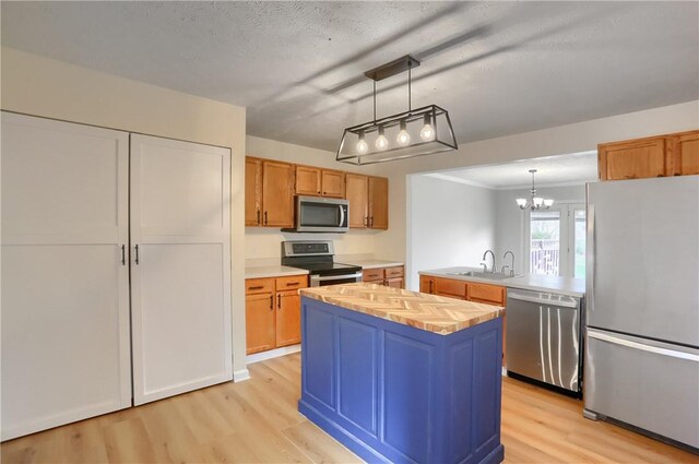 kitchen featuring an inviting chandelier, sink, appliances with stainless steel finishes, decorative light fixtures, and a kitchen island