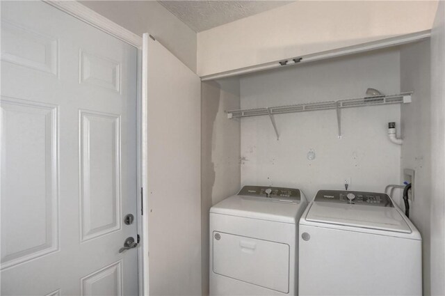 washroom featuring a textured ceiling and washer and clothes dryer