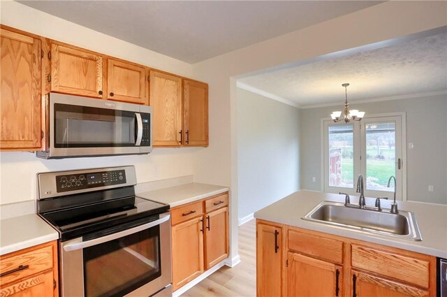 kitchen featuring pendant lighting, an inviting chandelier, sink, ornamental molding, and appliances with stainless steel finishes