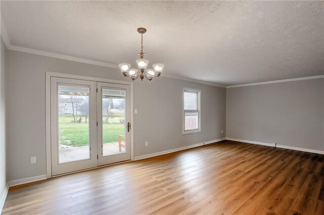 spare room with hardwood / wood-style flooring, ornamental molding, a textured ceiling, and an inviting chandelier