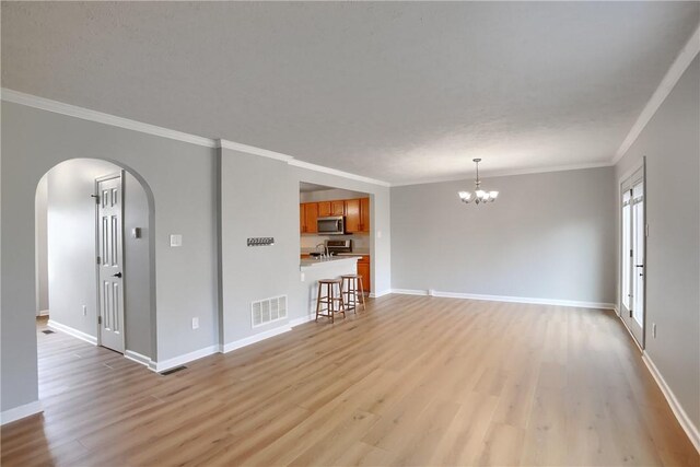 unfurnished living room featuring crown molding, sink, light hardwood / wood-style floors, and an inviting chandelier