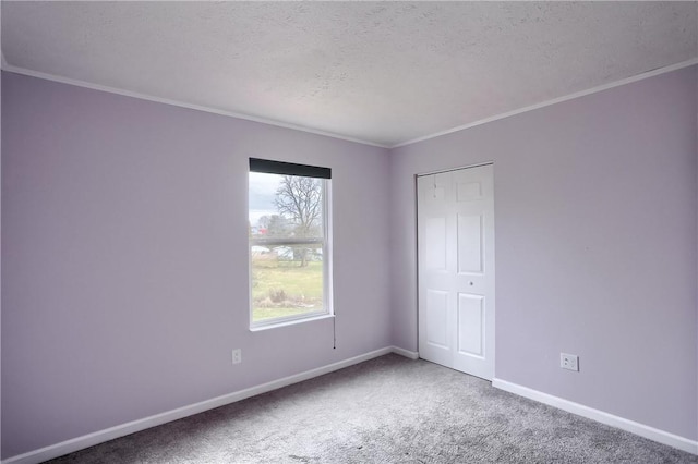 spare room featuring carpet, ornamental molding, and a textured ceiling