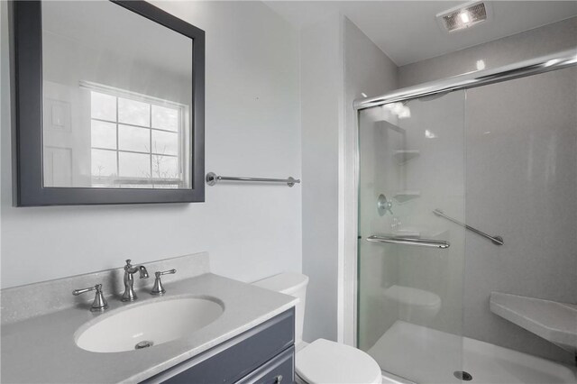 bathroom featuring vanity, toilet, and a shower with shower door