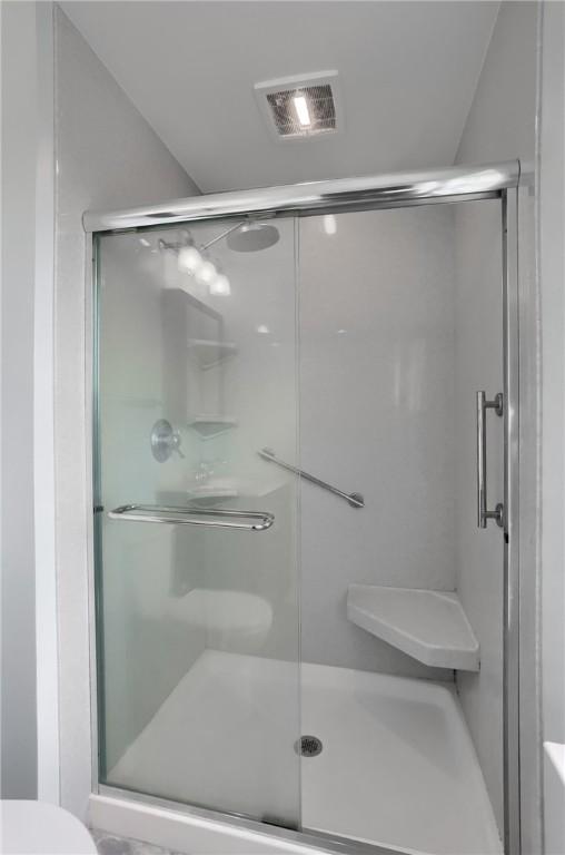 bathroom with toilet and a shower with door