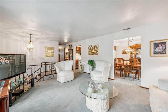 carpeted living room with an inviting chandelier