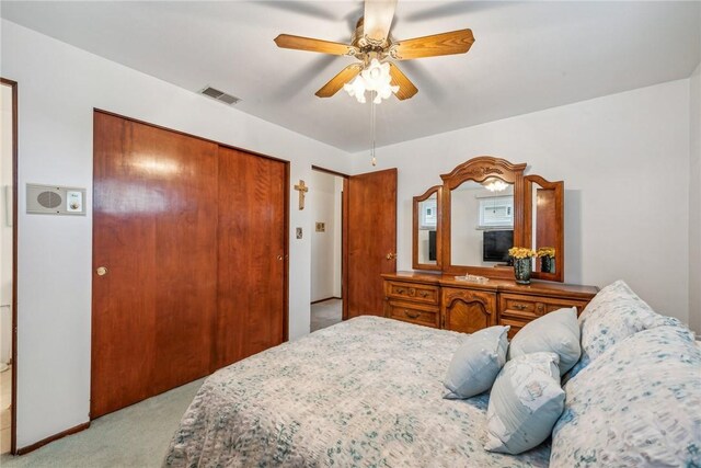 bedroom with ceiling fan, light colored carpet, and a closet