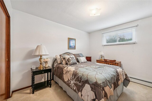 carpeted bedroom with baseboard heating and a closet