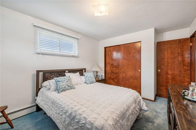 bedroom featuring dark colored carpet, a closet, and a baseboard heating unit