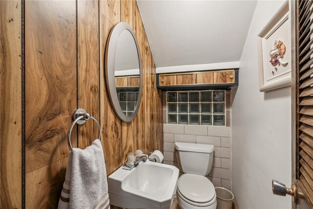 bathroom featuring sink, tile walls, and toilet