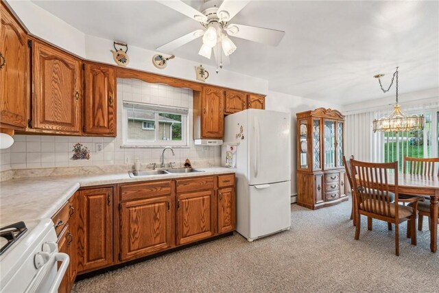 kitchen with stove, ceiling fan with notable chandelier, white refrigerator, sink, and decorative light fixtures