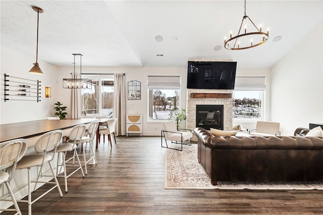 living room with dark hardwood / wood-style floors, lofted ceiling, and an inviting chandelier