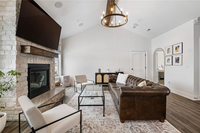 living room with a fireplace, wood-type flooring, lofted ceiling, and a notable chandelier