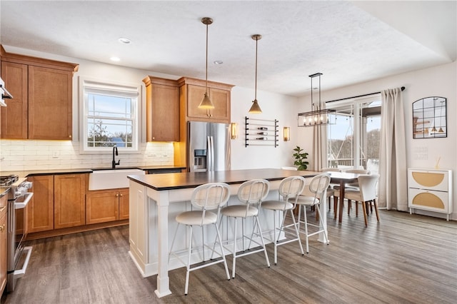 kitchen featuring dark hardwood / wood-style flooring, stainless steel appliances, sink, a center island, and hanging light fixtures