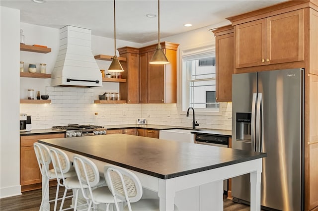 kitchen featuring sink, stainless steel appliances, dark hardwood / wood-style flooring, pendant lighting, and custom range hood