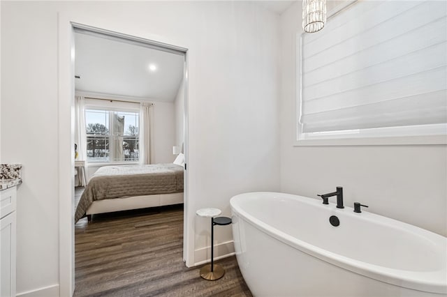 bathroom featuring lofted ceiling, vanity, hardwood / wood-style flooring, and a bathing tub