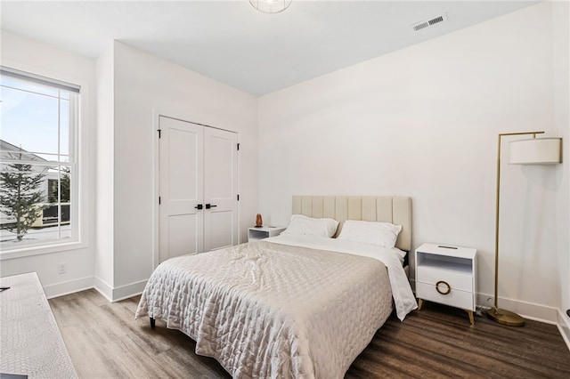 bedroom featuring dark hardwood / wood-style flooring, a closet, and multiple windows