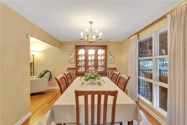 dining area with light hardwood / wood-style floors and a notable chandelier